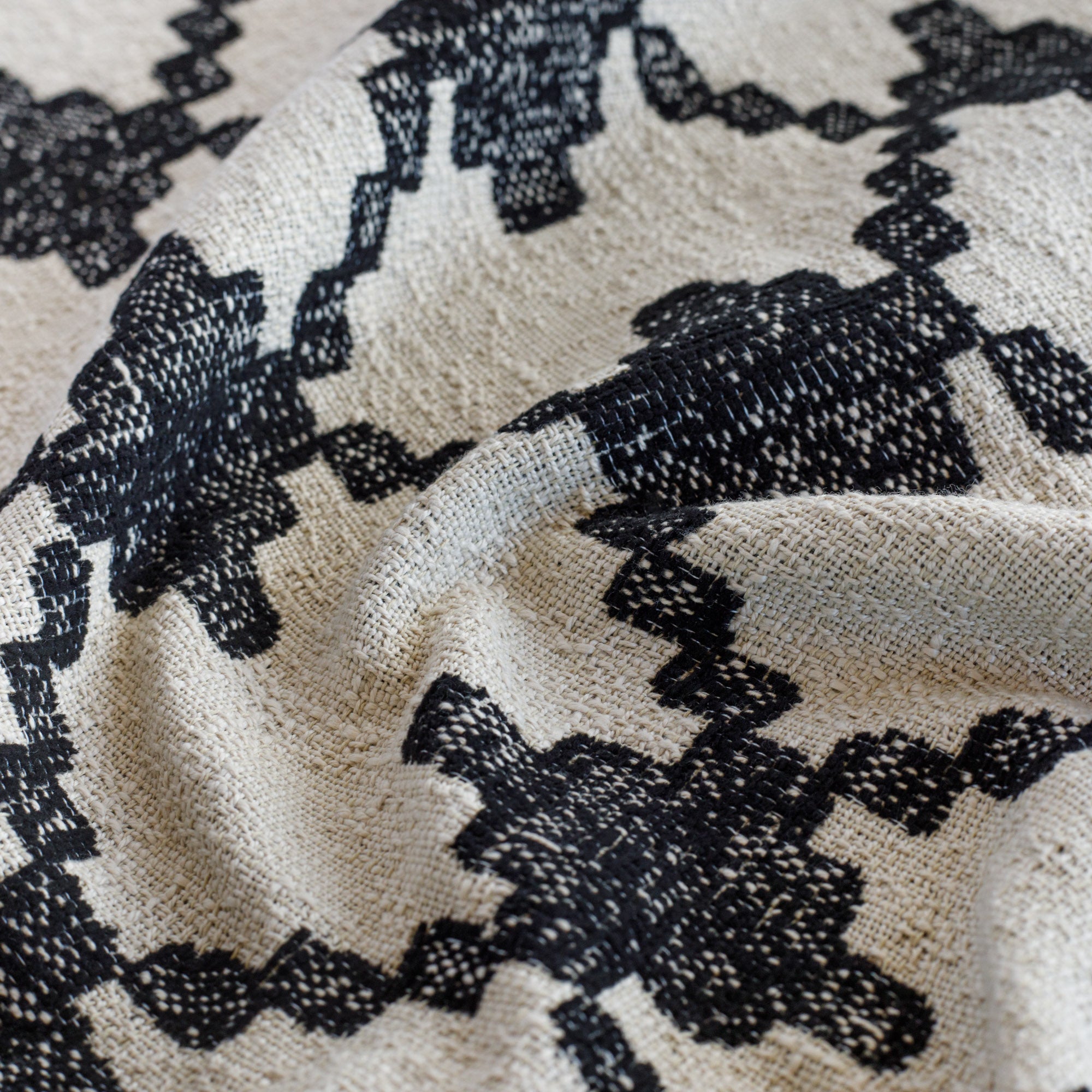 a black and natural abstract geometric patterned outdoor upholstery fabric : close up view