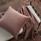 Tonic Living Florence Velvet mauve cushion styled on a bench with matching dusty purple velvet fabric.