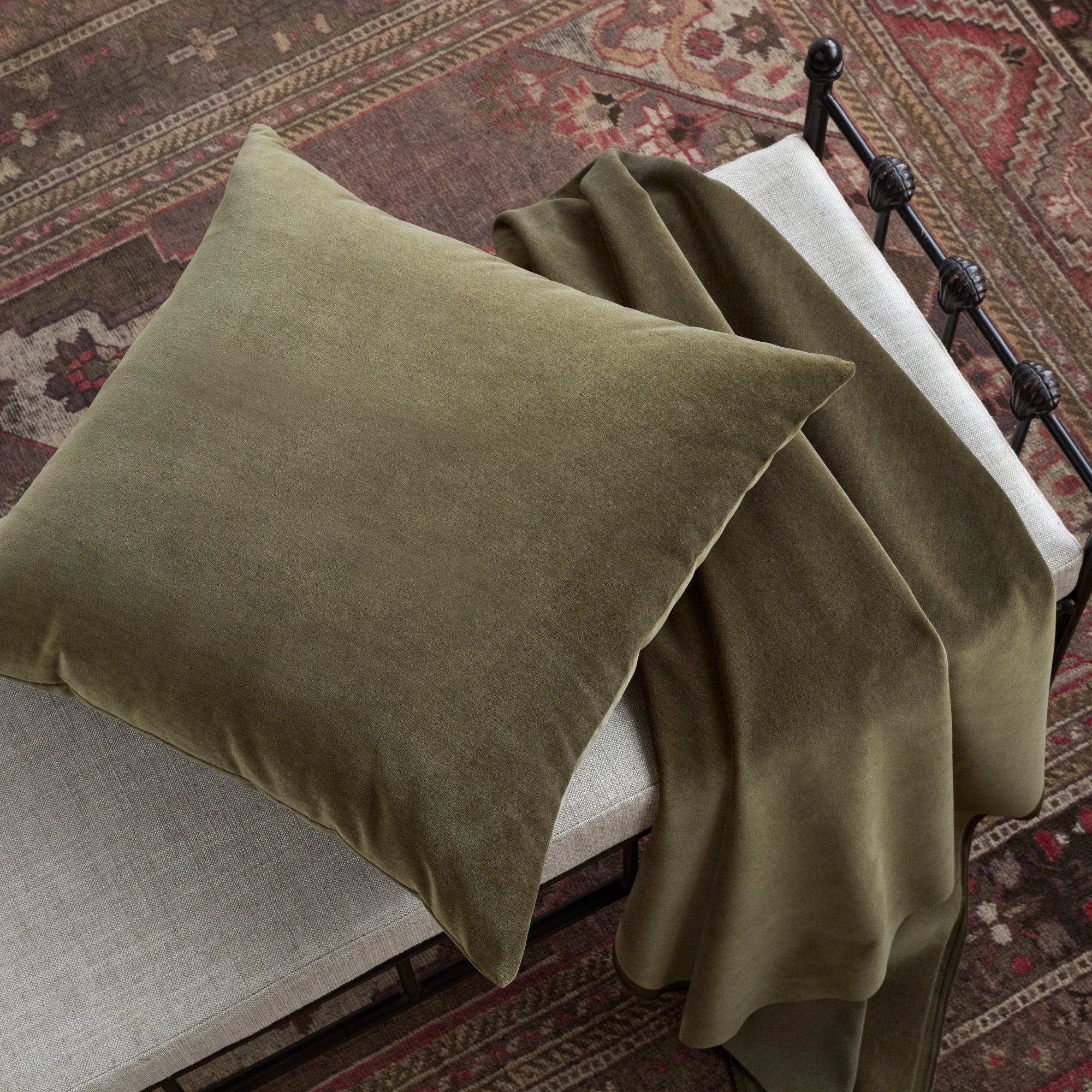 Tonic Living Florence Velvet Olive green cushion styled on a bench with matching green velvet upholstery fabric.