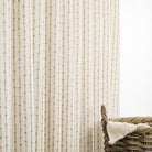 Tonic Living Hadley Stripe drapery fabric shown as striped curtains featuring blue and light brown bamboo-inspired detailing on an off-white ground.