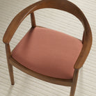 Tonic Living Hampton Rosewood high-performance upholstery fabric shown on a dining chair seat in a warm rose terracotta.