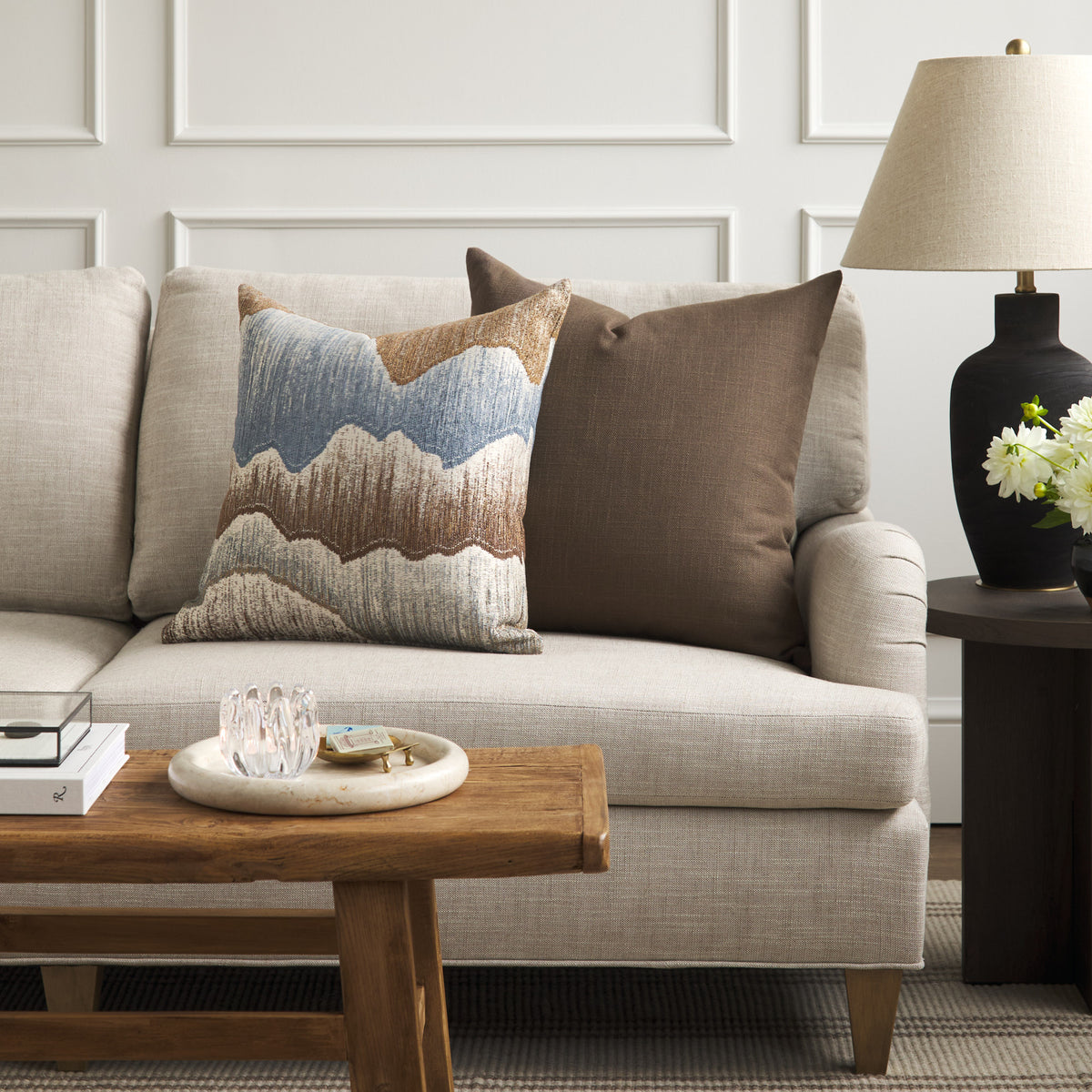 Tonic Living Hampton Walnut brown throw pillow styled on a sofa with Cortina Storm blue and brown abstract pillow.