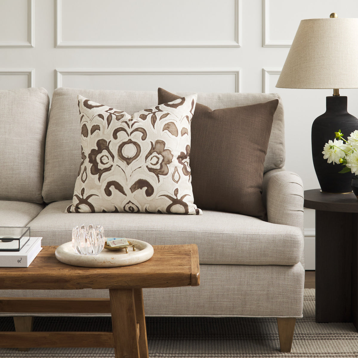 Tonic Living Hampton Walnut brown pillow styled on a sofa with Paloma Walnut floral throw pillow in a warm neutral living room.
