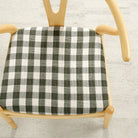 Tonic Living Henry Check Forest Green upholstery fabric shown on a chair seat with classic green gingham pattern.