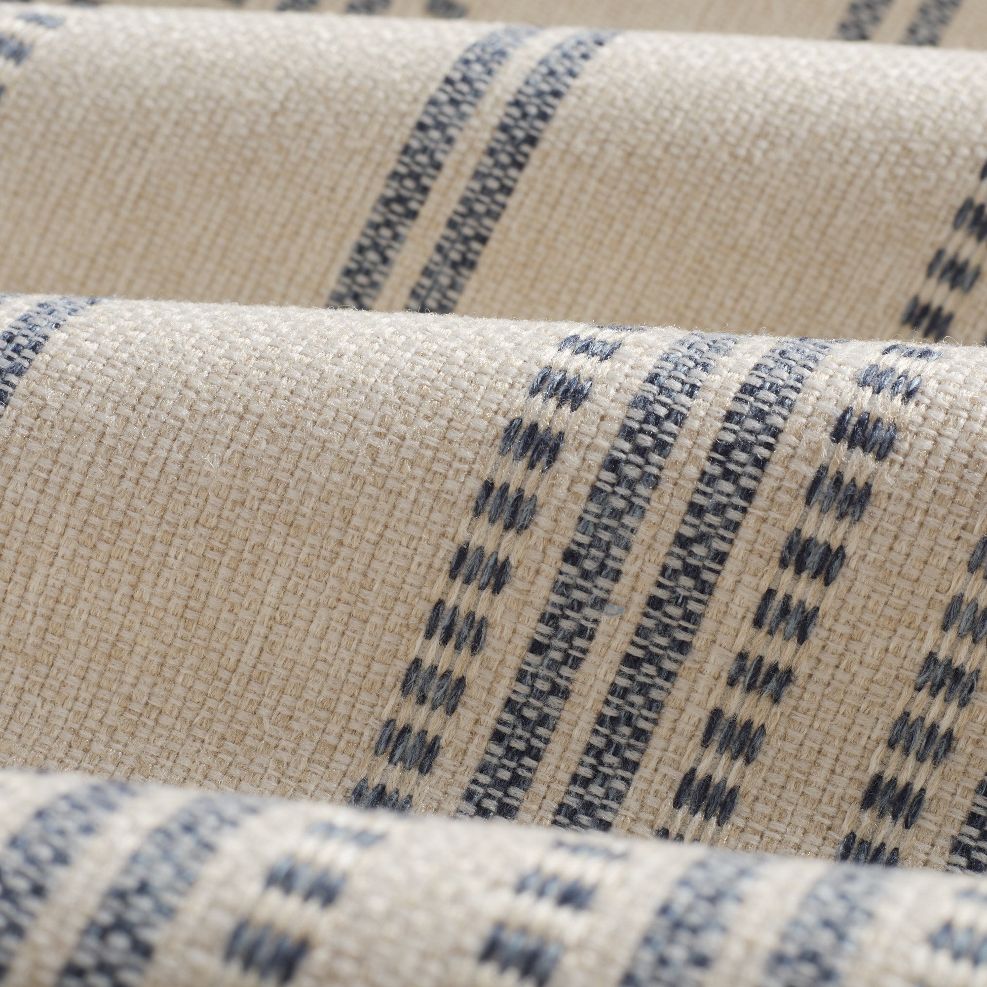 Close up of Tonic Living Hopper Stripe Denim fabric showing layered denim blue stripes over a light tan ground.