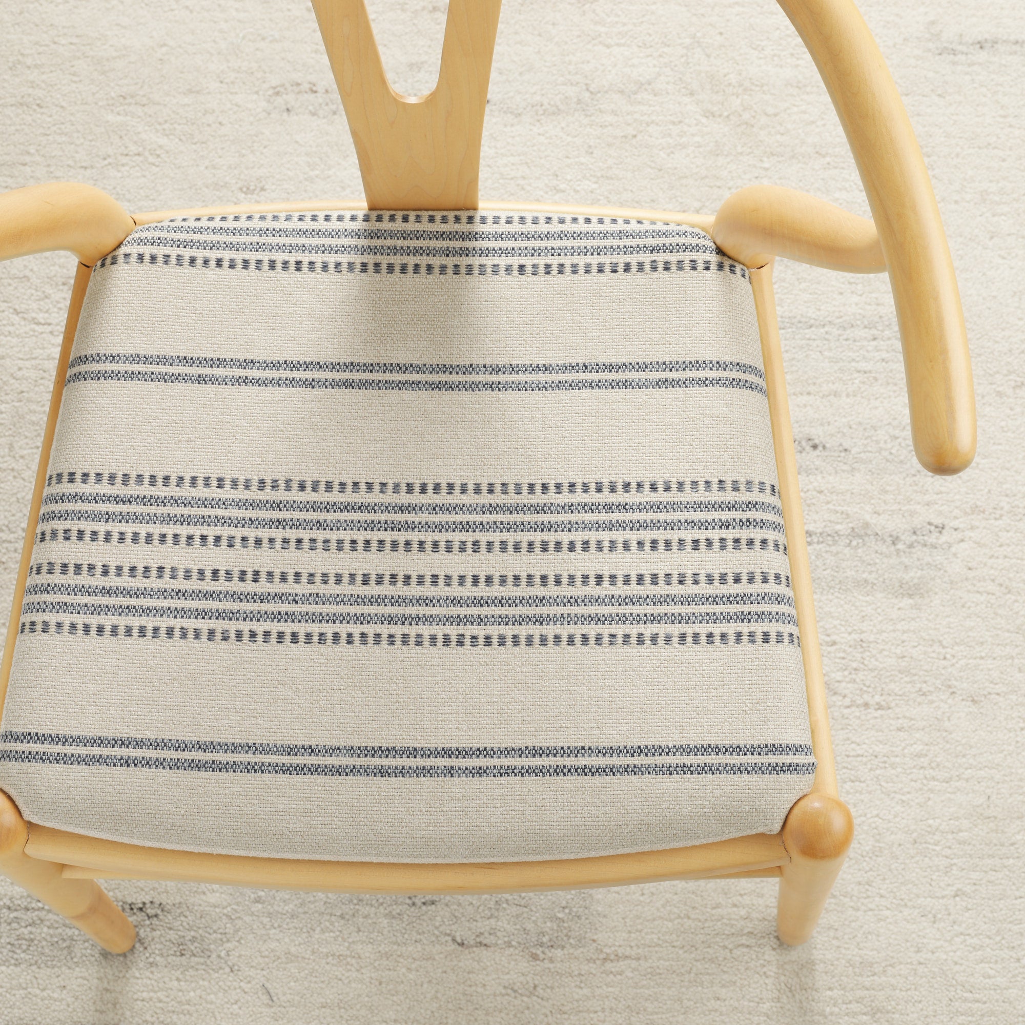 Tonic Living Hopper Stripe Denim high-performance upholstery fabric on a dining chair seat with blue stripes on tan.