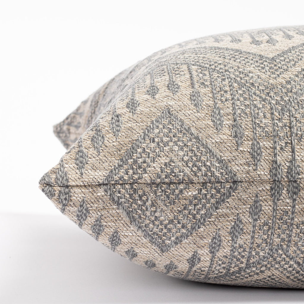 a grey and denim blue intricate zig zag patterned throw pillow : close up side view