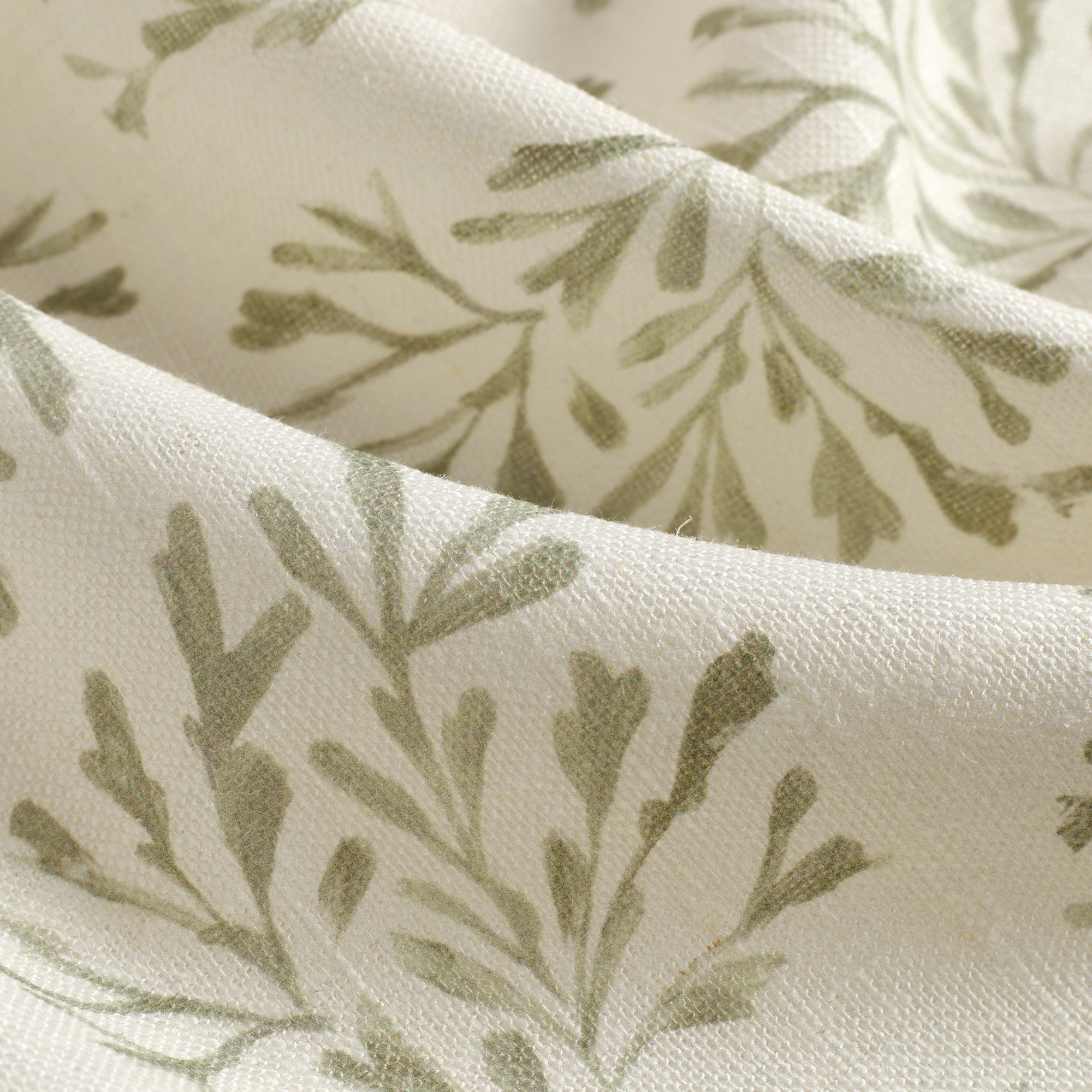 Close up of Tonic Living Juniper Sage fabric showing faded green and cream botanical sprig detail.