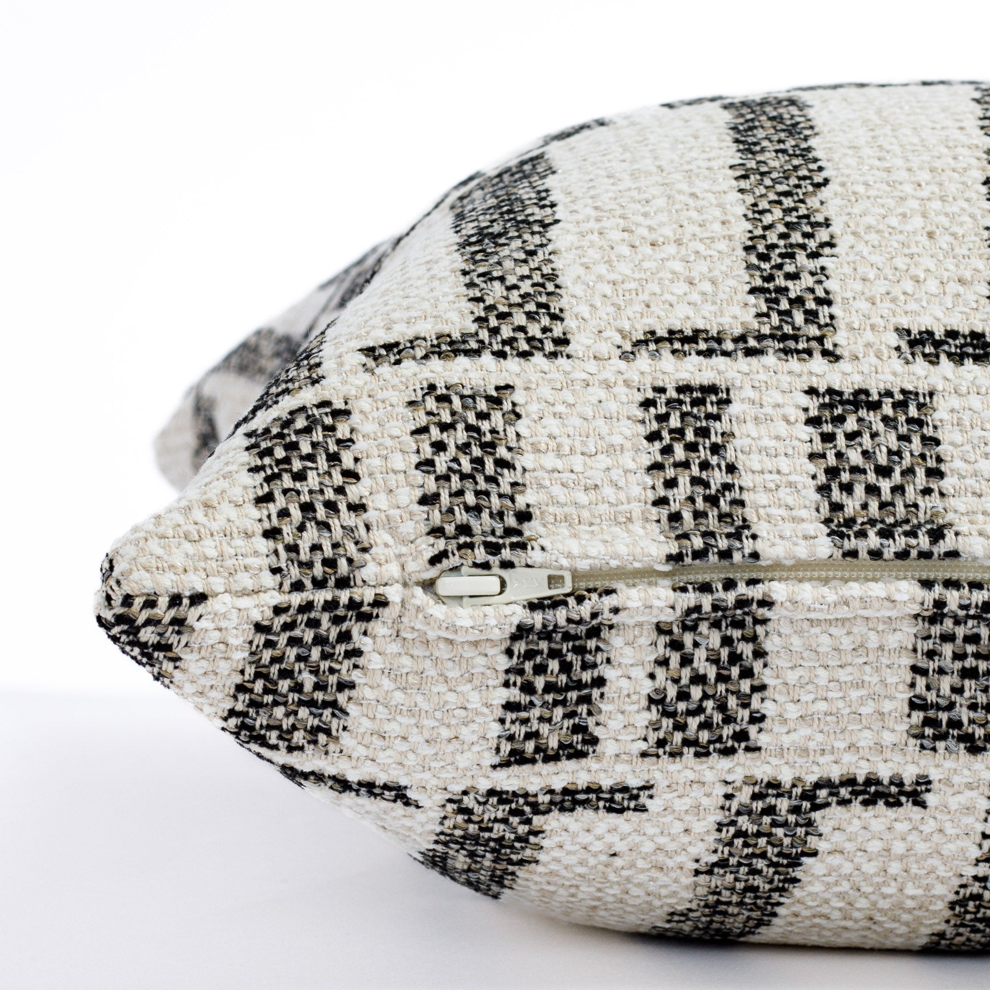 a cream and black organic geometric outdoor throw pillow : close up zipper view