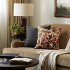 Tonic Living Marbella Rose floral pillow styled on a sofa with a neutral striped decorative cushion.