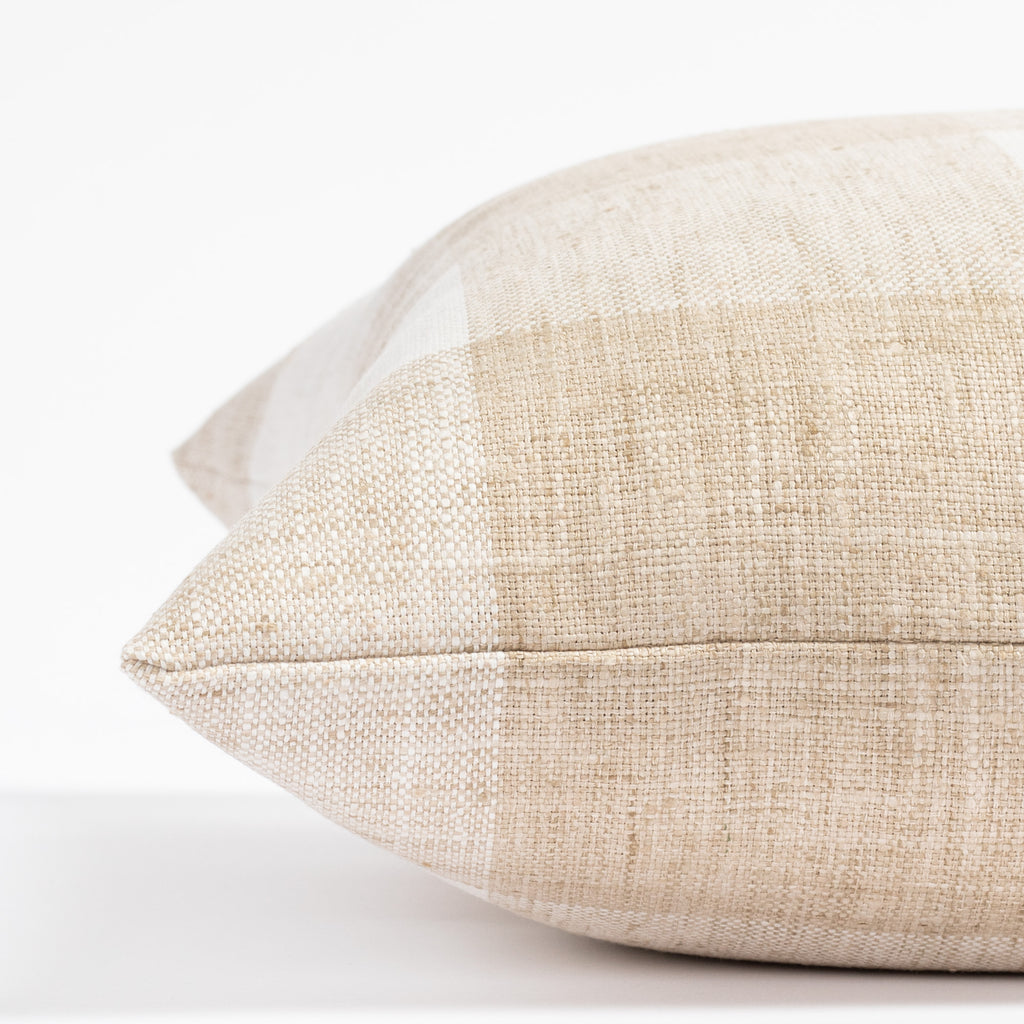 a white and beige check patterned throw pillow : close up side view