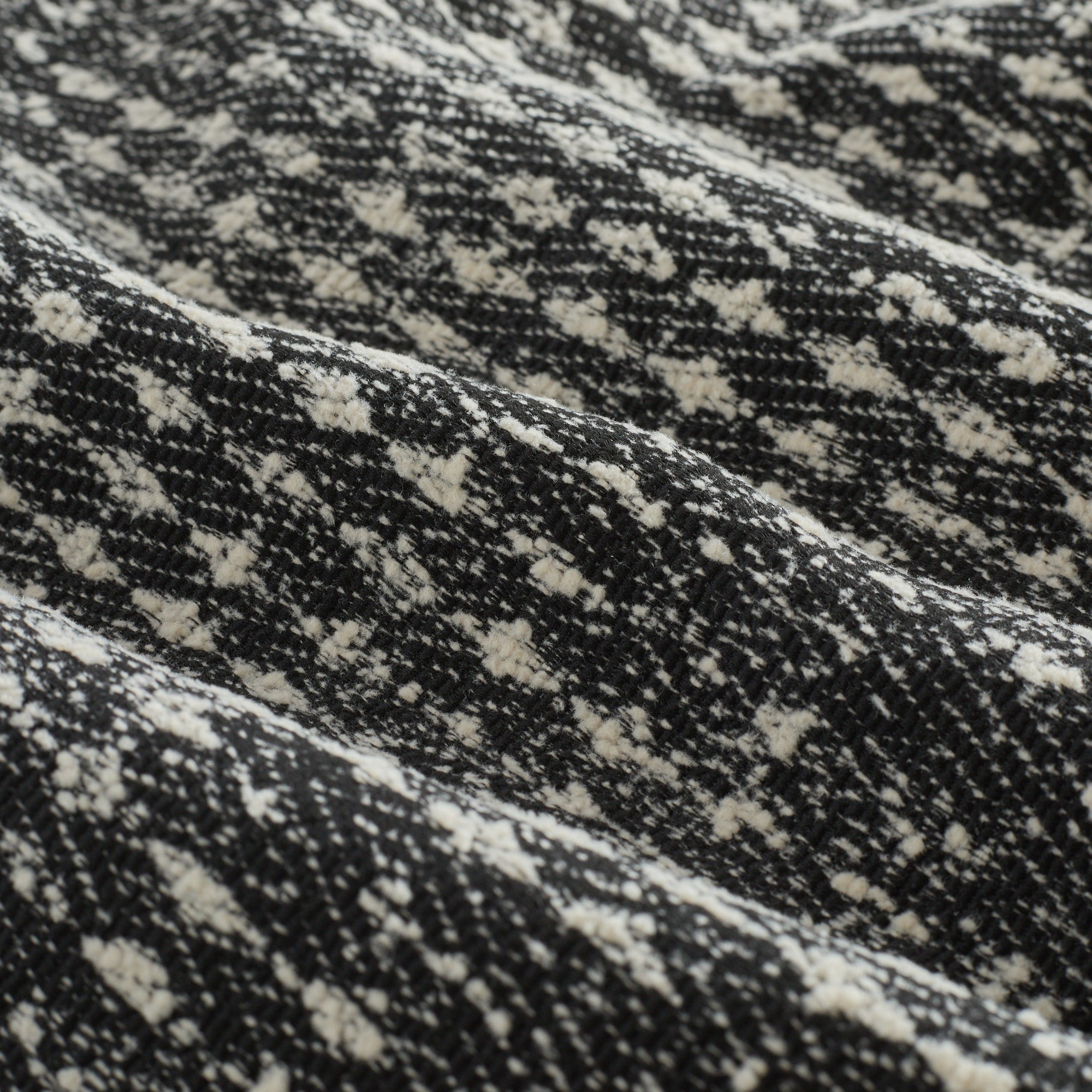 Close-up of Otto Fabric, Domino by Tonic Living — textured black and white weave with a bold, graphic houndstooth-inspired pattern.