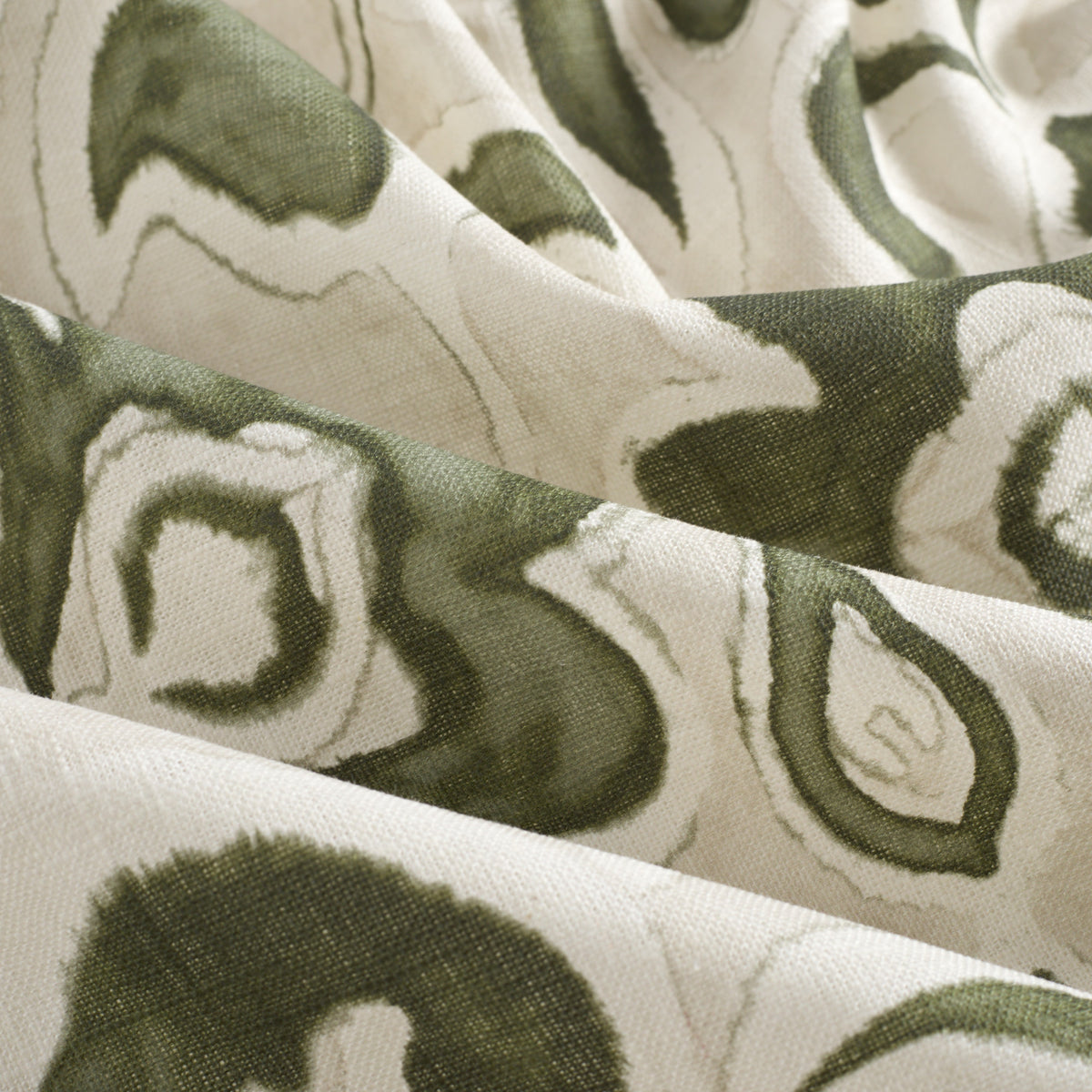 Close up of Tonic Living Paloma Olive drapery fabric showing stylized olive green flowers and scrolling leaves with a watercolour effect.