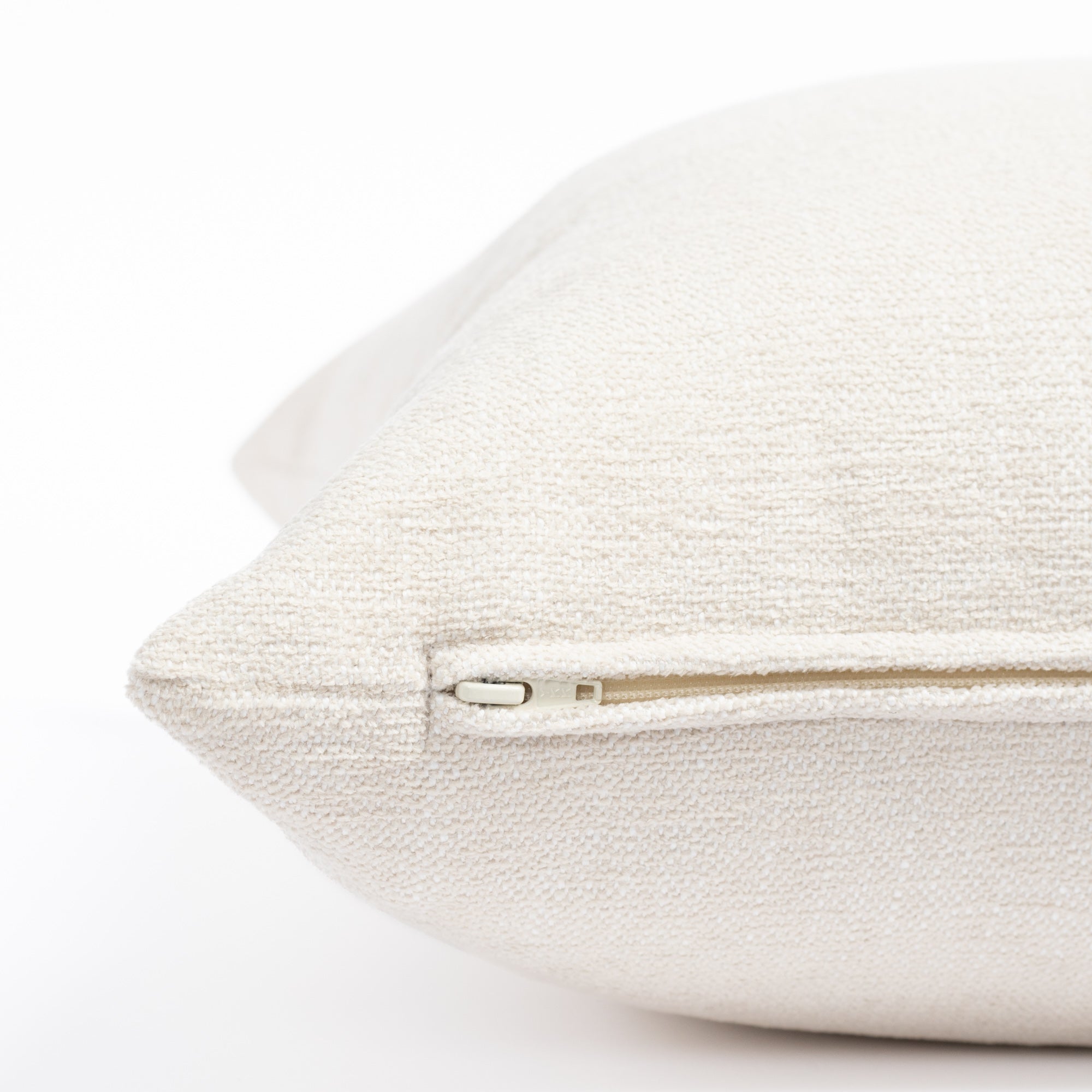 a cream indoor outdoor throw pillow: close up zipper view