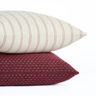 Stack of Pembrook 20x20 burgundy red pillow with Rexton Stripe cushion in beige and burgundy, Tonic Living.