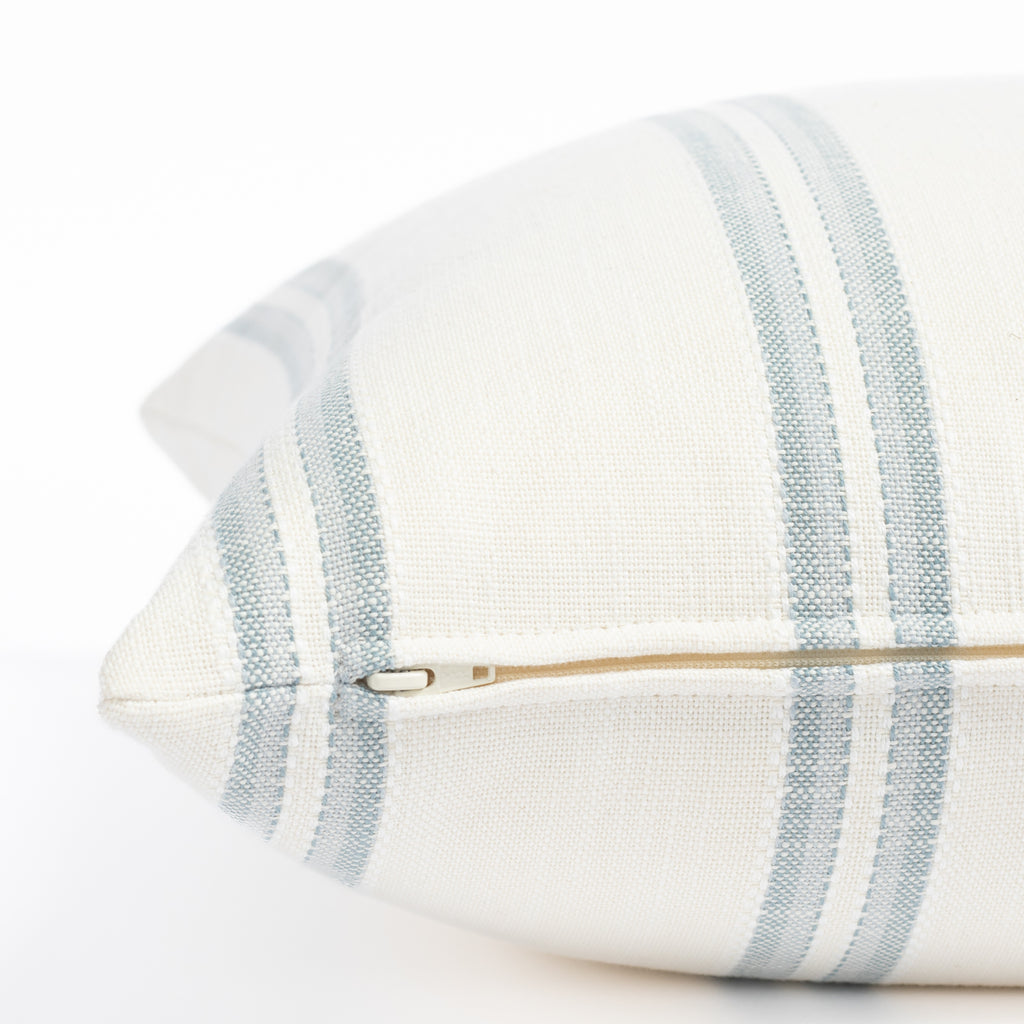 a white and chambray blue striped outdoor throw pillow : close up zipper view