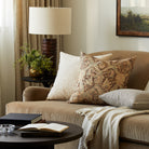 Tonic Living Zuri Driftwood decorative pillow styled on a brown velvet sofa with neutral textured cushions in an earthy living room.