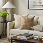 Tonic Living Walker Plaid Camel decorative cushion styled on a sofa with neutral textured throw pillows in a warm living room.