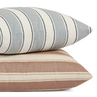 Stack of Tonic Living Sentiment 20x20 outdoor pillows in terracotta and denim blue featuring bold stripe designs.