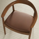 Tonic Living Smythe Cognac faux leather upholstery fabric shown on a dining chair seat in a rich cognac brown.