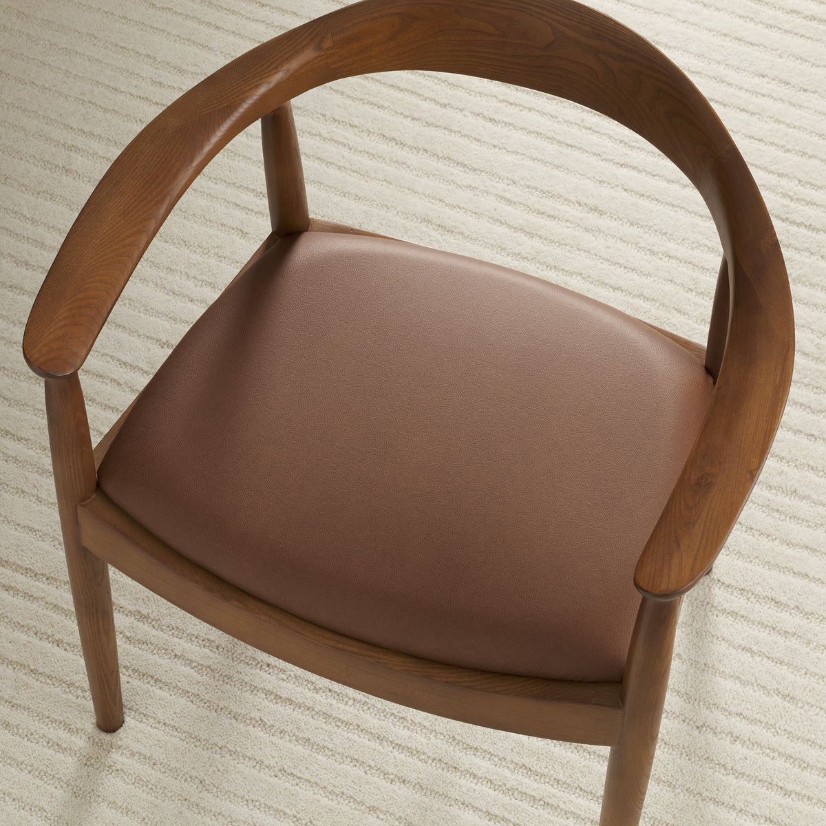 Tonic Living Smythe Cognac faux leather upholstery fabric shown on a dining chair seat in a rich cognac brown.