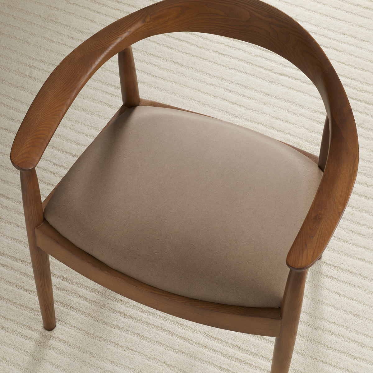 Tonic Living Smythe Portobello faux leather upholstery fabric shown on a dining chair seat in a warm taupe brown.