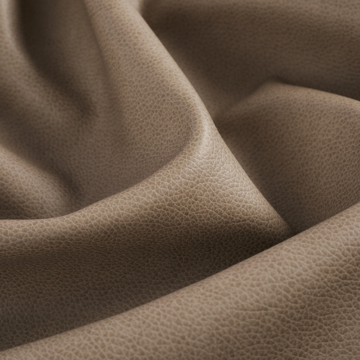 Close up of Tonic Living Smythe Portobello faux leather upholstery fabric showing its taupe brown colour and realistic leather grain.