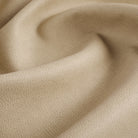 Close up of Tonic Living Smythe Sandstone faux leather upholstery fabric showing its sandy beige colour and realistic leather grain.