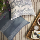 Overhead view of Tonic Living Swoon Denim blue decorative cushion with Caper Slate pillow on an outdoor rug.
