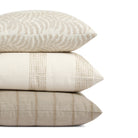 Stack of Tonic Living outdoor pillows including Swoon Sand, Caper Linen, and Talisman Sand in soft neutral tones.