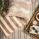 Overhead view of Tonic Living Swoon Terracotta decorative cushion with Sentiment Terracotta pillow on an outdoor rug.