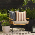 Tonic Living Sentiment Terracotta throw pillow styled on a chair with Talisman Denim 22x22 cushion outdoors.