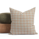 Vesper Plaid 20x20 houndstooth check cushion in beige, blue, and rust, shown with green and brown pillows.