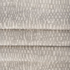 Avareno Silver, a light gray and sandy beige small scale abstract print fabric : close up with soft folds