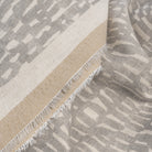 Avareno Silver, a light grey and sandy beige small scale abstract print fabric : close up selvage edge