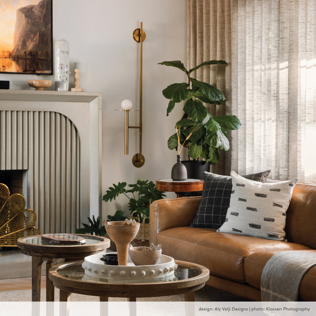 living room with brown leather sofa and brass accessories with tonic living pillows.