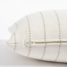 a cream and gray vertical striped pillow : zipper detail