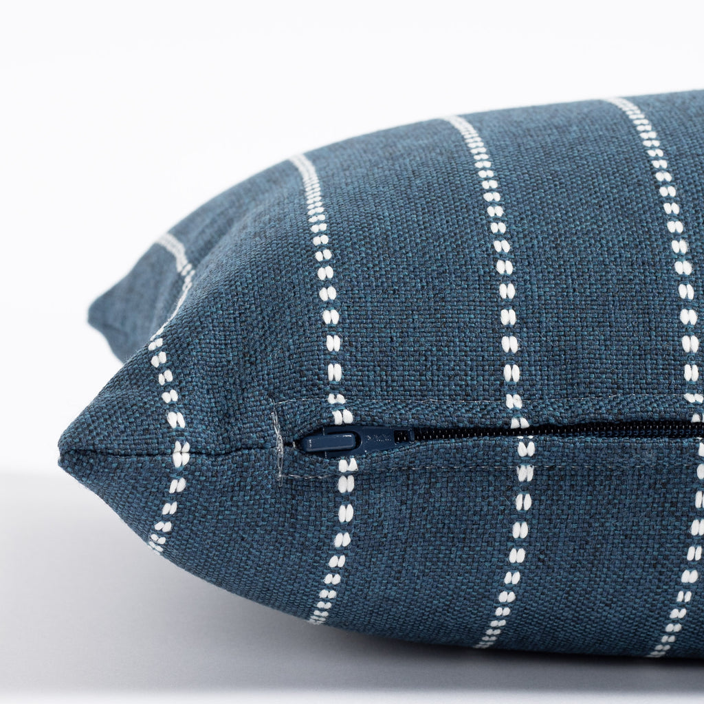 a navy blue and white stripe pillow : zipper detail