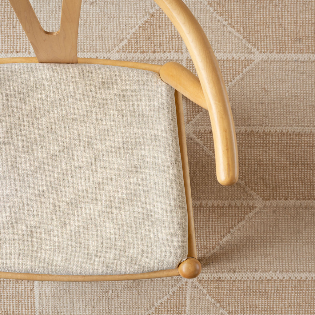 Grange Fabric Parchment, a high performance sandy beige upholstery fabric shown on a chair seat