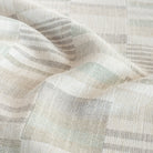 a geometric patchwork patterned upholstery fabric in costal watery green, sand, and gray colours