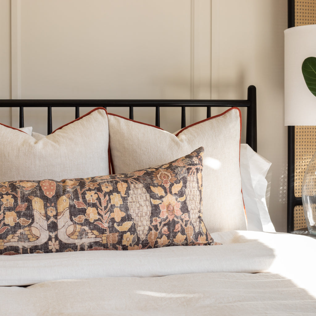 a cozy pillow with a beautiful botanical print in warm earthy colours with cleary twine pillow on a bed