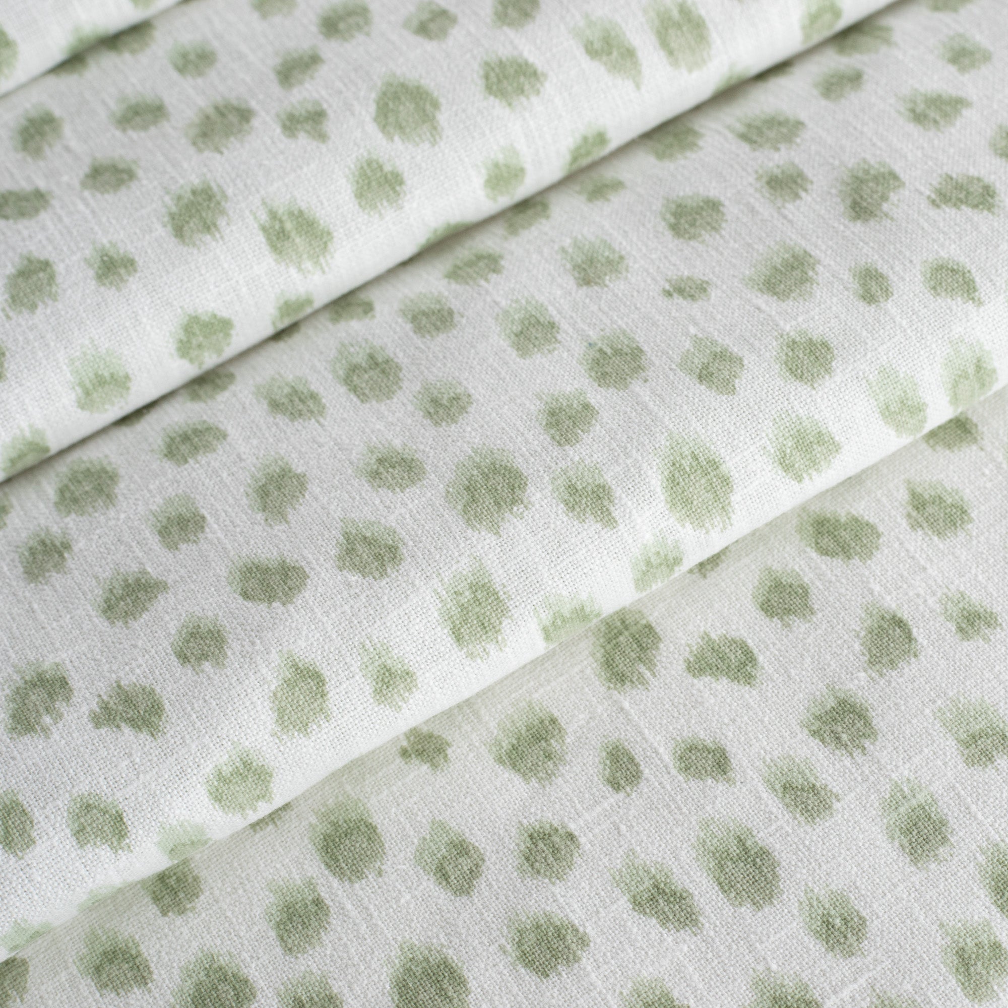 a white and green inky polka dot print fabric