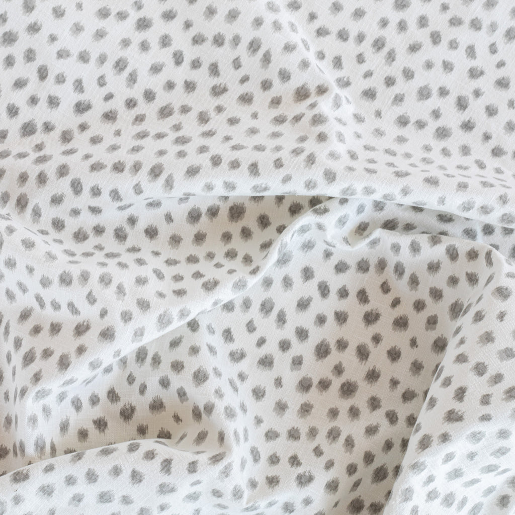 a white and silver grey inky polka dot print fabric by the yard