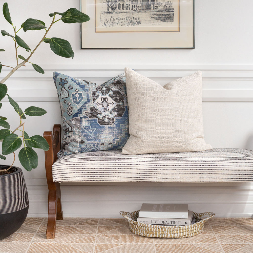 Home decor vignette: Milly cream pillow with Saro blue tapestry pattern pillow on Misto cream and black stripe fabric bench