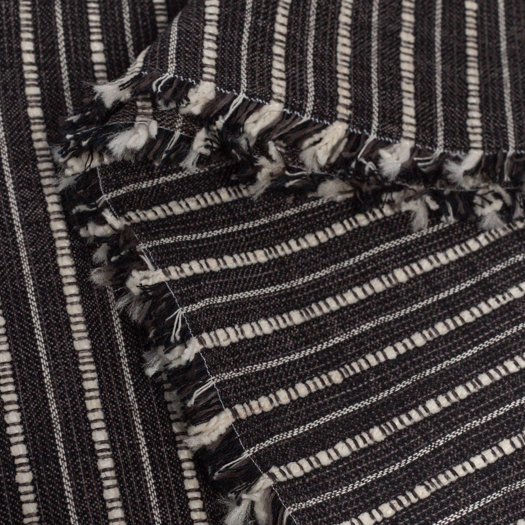 Misto Stripe Charcoal, a faded black and cream striped Crypton home performance fabric : selvage edge view